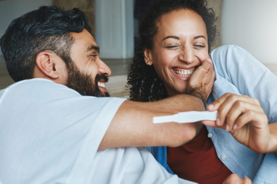 Man and woman smiling at positive pregnancy test.